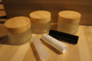 glass Containers/pots with wooden lids to store natural organic skincare cosmetic products in and plastic tubes to store organic lip balm in